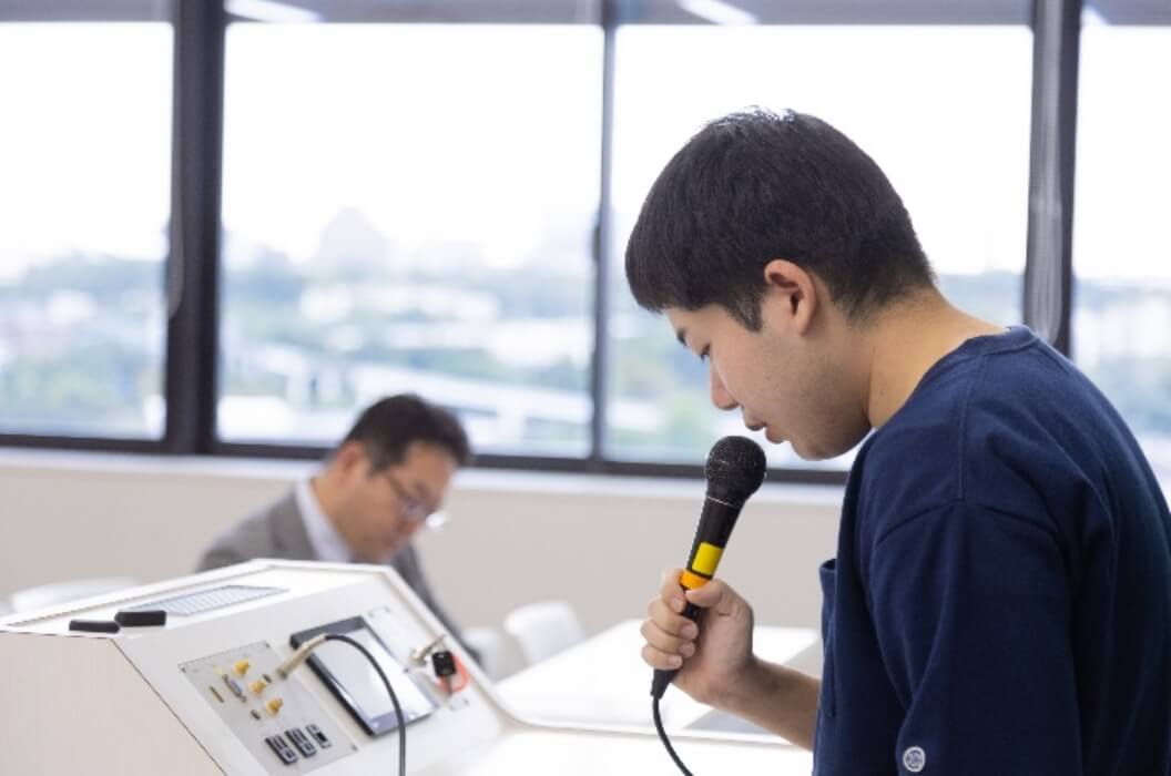 男性生徒が卒業論文の進捗報告会を行なう様子