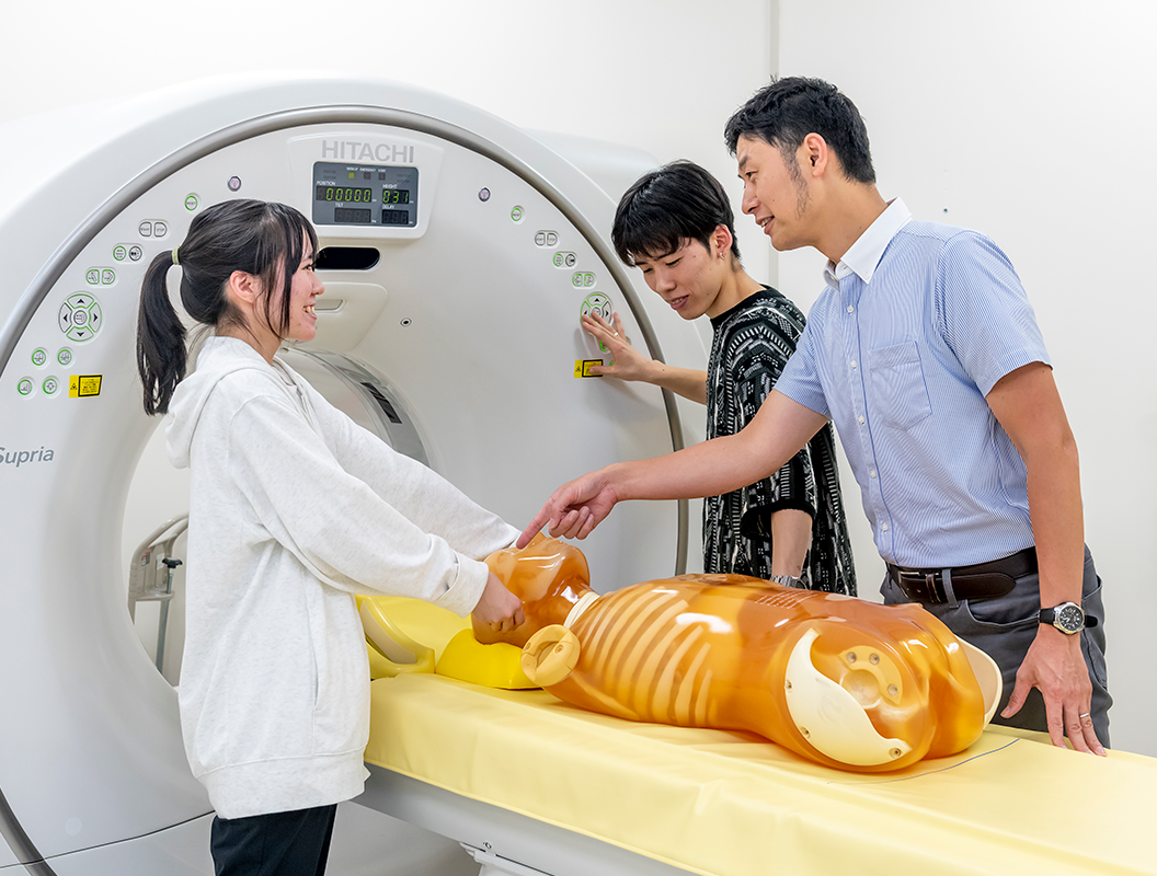 亀澤准教授と生徒が診断機器の前に立ち、実習している様子